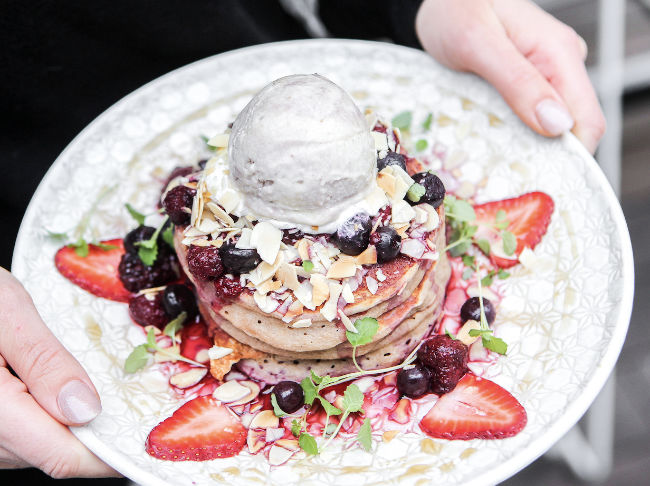 vegan pancakes served on a plate and topped with fruit, ice cream and nuts