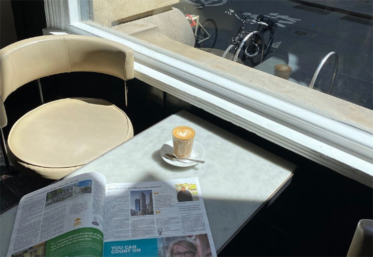 a coffee sitting next to a newspaper on a table in a coffee shop