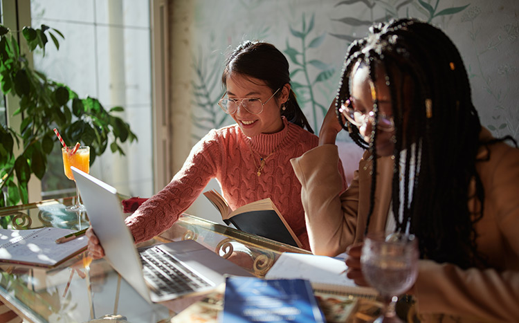 two ladies sitting together working at a cafe