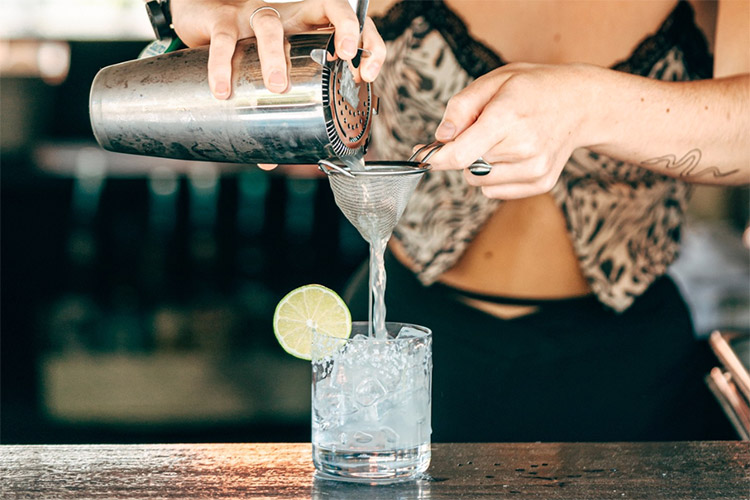 a waitress pouring a cocktail into a glass